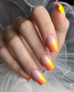 Wiosenny manicure żelowy w stylu ombre, w odcieniach żółci i pomarańczy, z delikatnymi wzorami – inspiracja na lato z salonu w Krakowie.